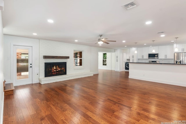 unfurnished living room featuring a fireplace, ceiling fan, hardwood / wood-style floors, and washer / dryer