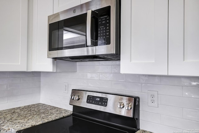 interior details with decorative backsplash, stainless steel appliances, white cabinetry, and light stone counters