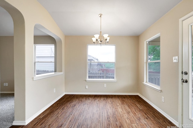 unfurnished dining area with dark hardwood / wood-style flooring and an inviting chandelier