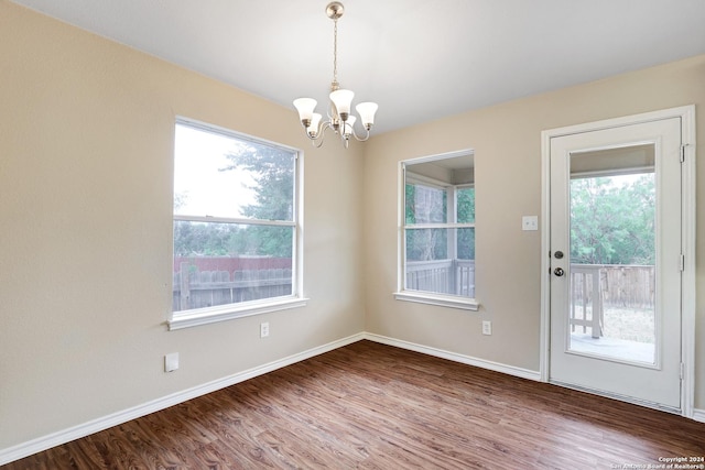 unfurnished dining area with a chandelier and hardwood / wood-style flooring