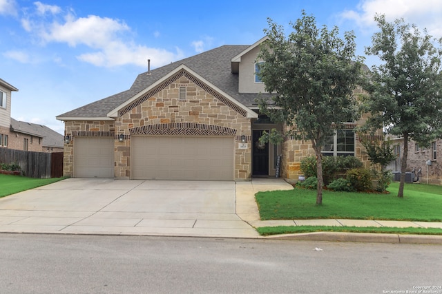 view of front of property featuring a garage, a front yard, and central AC unit