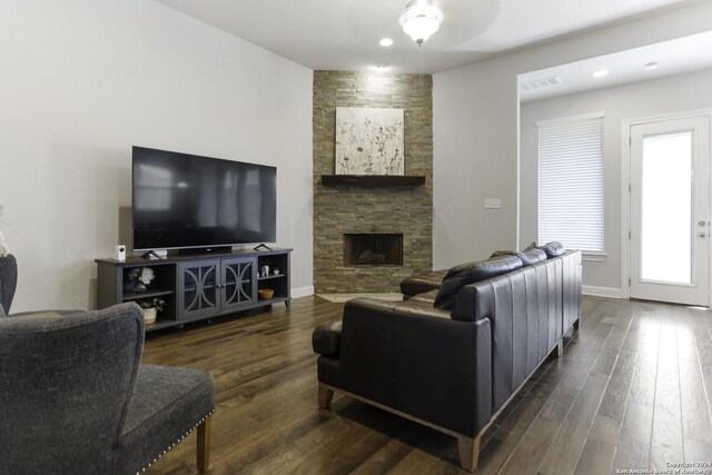 living room featuring a stone fireplace and dark hardwood / wood-style flooring