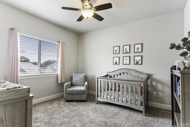 bedroom with carpet, ceiling fan, and a nursery area