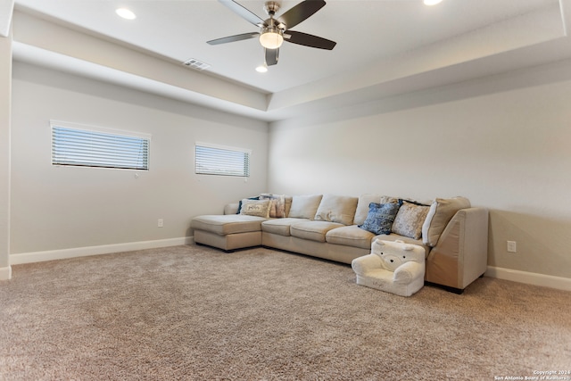 living room with ceiling fan, carpet flooring, and a tray ceiling