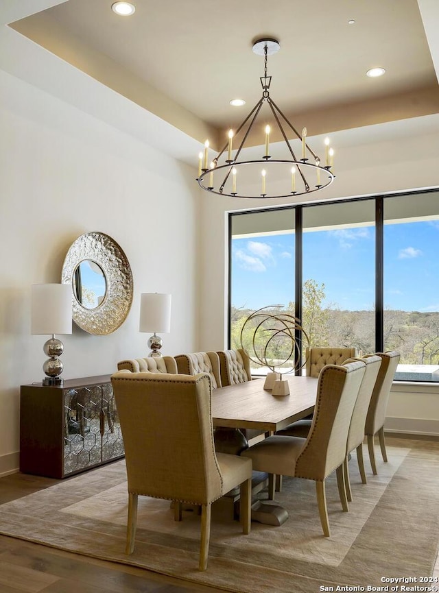 dining area featuring wood-type flooring, a tray ceiling, and a chandelier