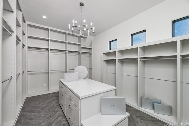 walk in closet with dark parquet floors and a chandelier