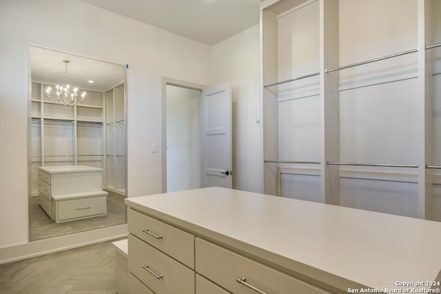 spacious closet featuring an inviting chandelier and parquet floors