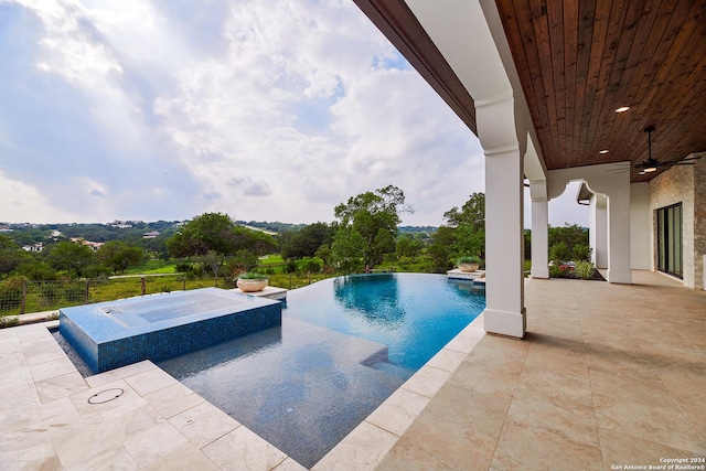 view of swimming pool featuring pool water feature, ceiling fan, a patio area, and an in ground hot tub