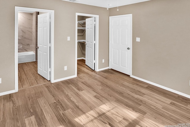 unfurnished bedroom featuring a walk in closet, light hardwood / wood-style flooring, and a closet