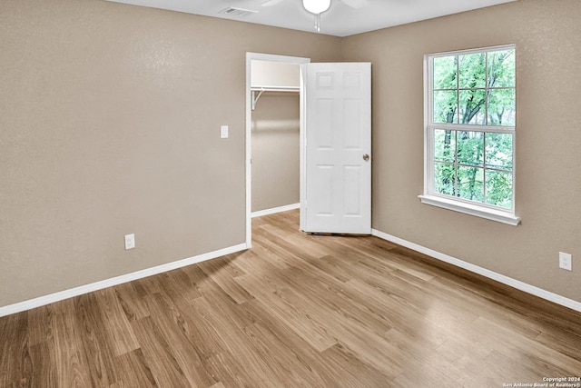 unfurnished bedroom with ceiling fan, multiple windows, light hardwood / wood-style flooring, and a closet