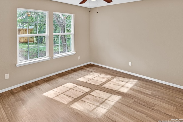 empty room featuring ceiling fan, light wood-type flooring, and a wealth of natural light