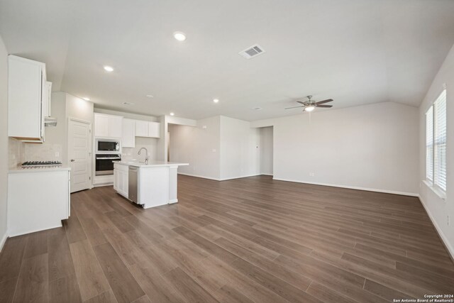 kitchen with white cabinets, appliances with stainless steel finishes, sink, backsplash, and a kitchen island with sink