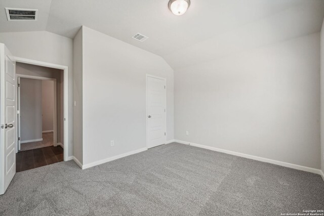 carpeted empty room with vaulted ceiling