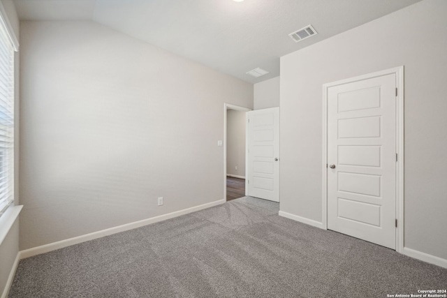 unfurnished bedroom featuring vaulted ceiling and carpet