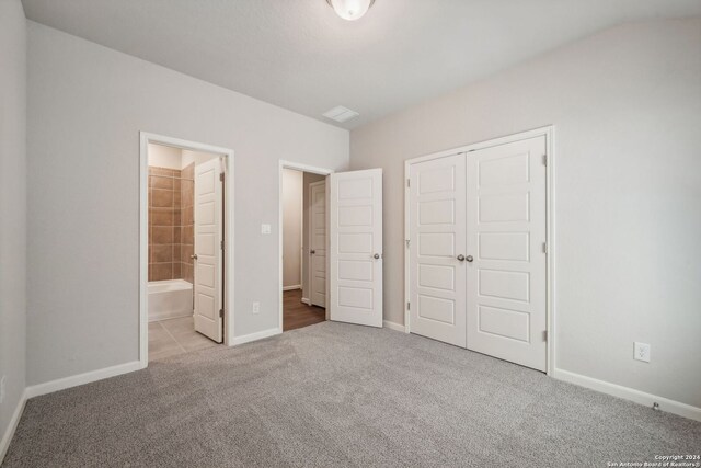 unfurnished bedroom with ensuite bathroom, a closet, and light carpet