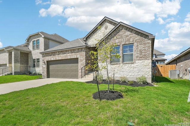 view of front of home with a garage, a front yard, and central AC unit