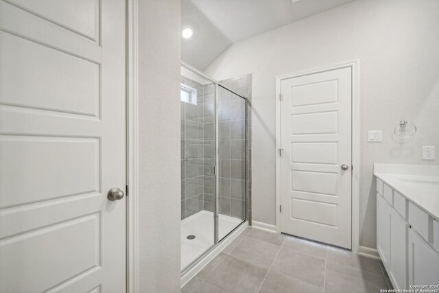 bathroom featuring an enclosed shower, vanity, tile patterned floors, and lofted ceiling