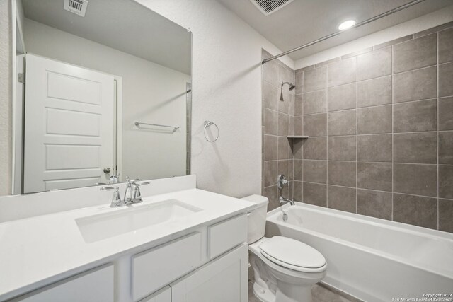 full bathroom with toilet, tiled shower / bath, and vanity