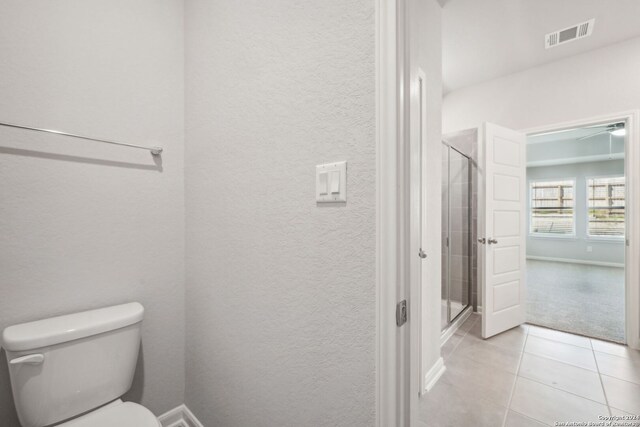 bathroom with toilet, a shower with door, and tile patterned floors