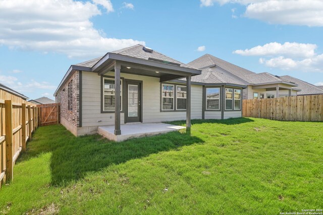 back of house with a lawn and a patio