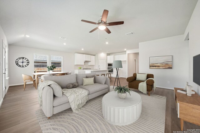 living room featuring light wood-type flooring, ceiling fan, and sink