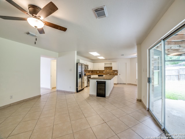 kitchen featuring stainless steel appliances, a kitchen island, ceiling fan, light tile patterned floors, and white cabinetry