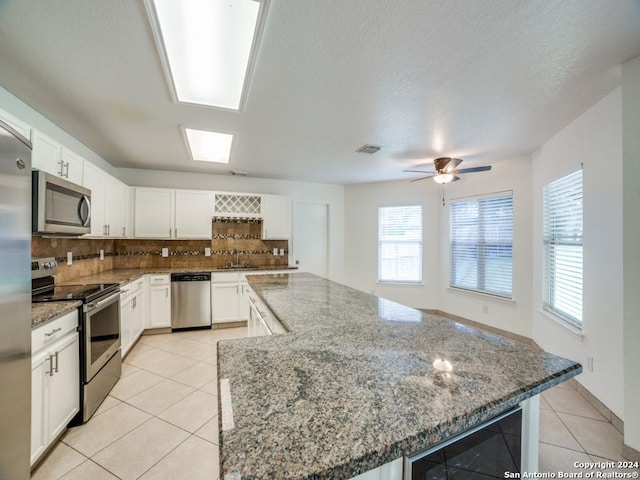 kitchen featuring sink, beverage cooler, stone countertops, white cabinets, and appliances with stainless steel finishes