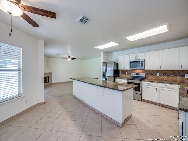 kitchen with white cabinetry, backsplash, dark stone counters, light tile patterned flooring, and appliances with stainless steel finishes