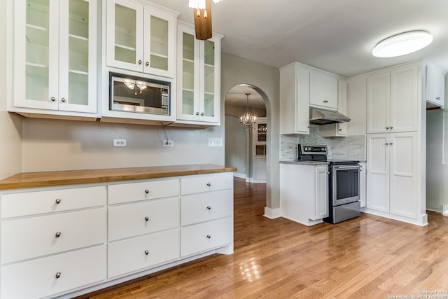 kitchen featuring butcher block countertops, white cabinetry, hanging light fixtures, and stainless steel appliances