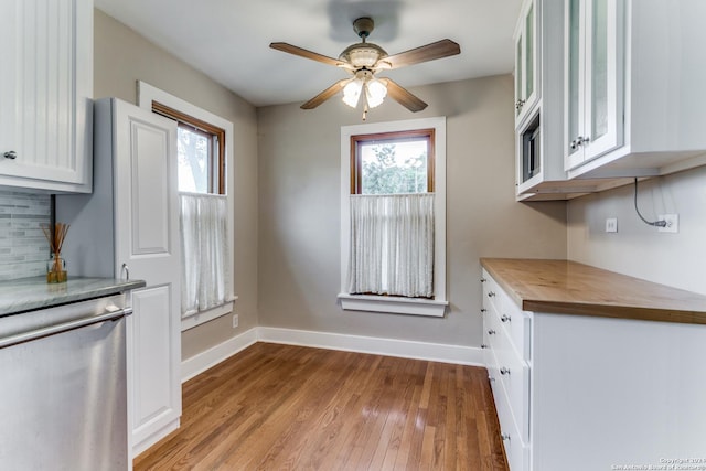 kitchen with dishwasher, butcher block countertops, white cabinetry, and plenty of natural light