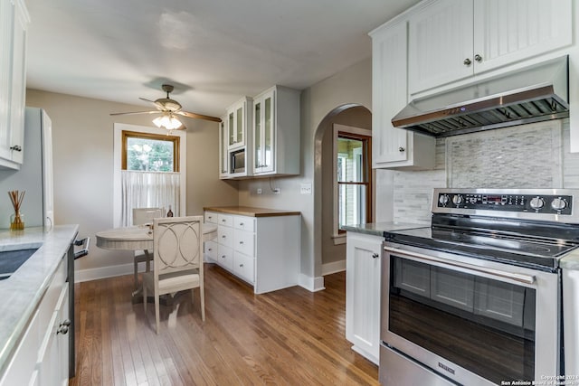 kitchen featuring hardwood / wood-style floors, backsplash, stainless steel electric stove, ceiling fan, and white cabinetry