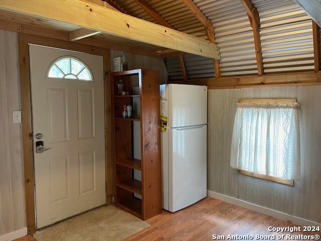 foyer with hardwood / wood-style floors, wooden walls, and lofted ceiling