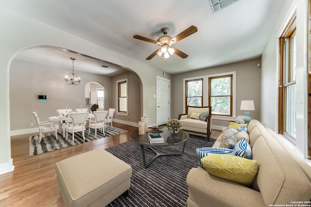 living room featuring ceiling fan with notable chandelier and light wood-type flooring