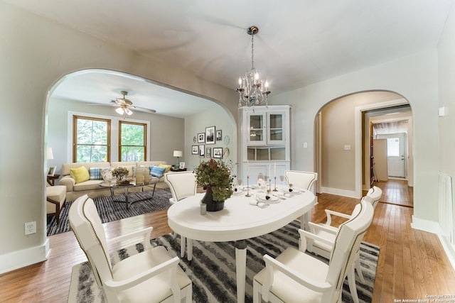 dining area with ceiling fan with notable chandelier and light hardwood / wood-style flooring