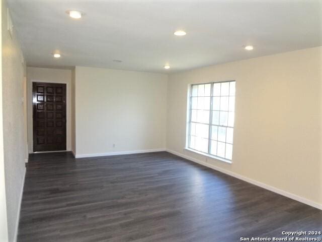 spare room featuring recessed lighting, dark wood-style floors, and baseboards