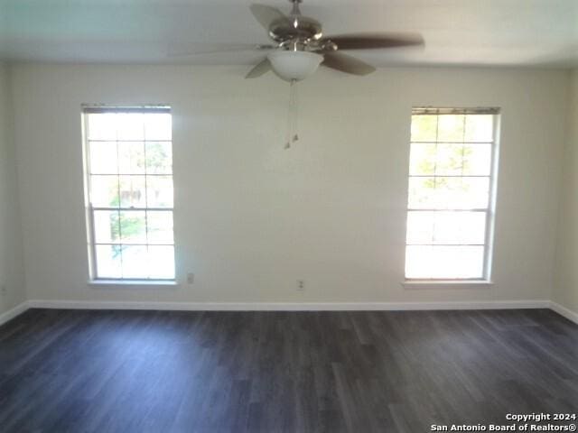 unfurnished room featuring baseboards, dark wood finished floors, and a ceiling fan