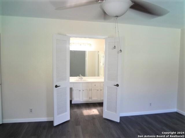 unfurnished bedroom with ensuite bathroom, ceiling fan, dark hardwood / wood-style floors, and sink