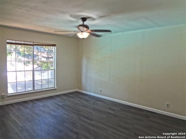 spare room with ceiling fan, baseboards, and dark wood-style floors