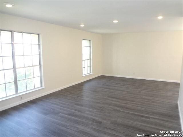 spare room featuring a wealth of natural light, recessed lighting, baseboards, and dark wood-style flooring