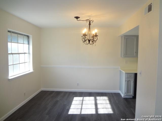 empty room featuring dark hardwood / wood-style flooring and an inviting chandelier