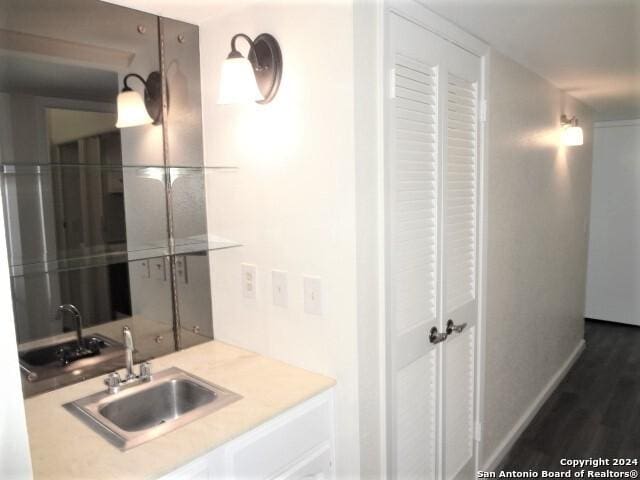 bathroom with wood finished floors, baseboards, and a sink