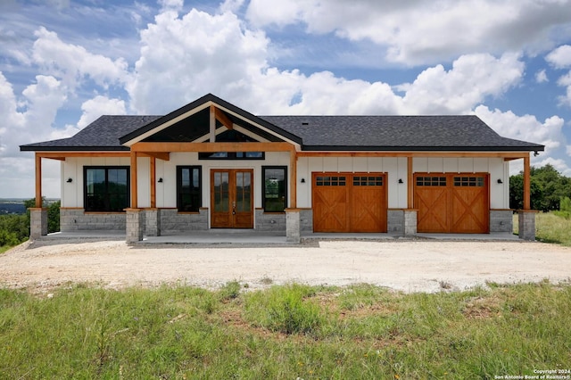 view of front of property featuring a porch, a garage, and french doors