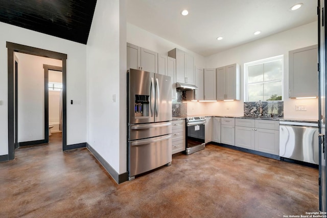 kitchen with backsplash, concrete flooring, light stone counters, stainless steel appliances, and sink