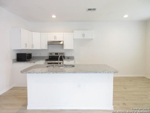 kitchen featuring stainless steel appliances, white cabinets, and a center island with sink