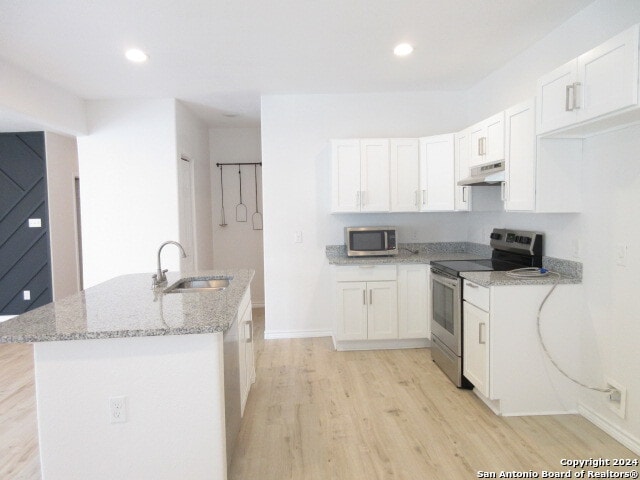 kitchen with white cabinets, light hardwood / wood-style floors, stainless steel appliances, light stone countertops, and sink