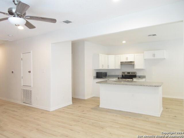 kitchen featuring light stone counters, electric range, an island with sink, and white cabinets