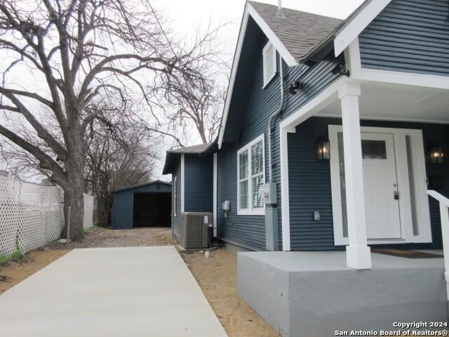 view of property exterior featuring central AC, a porch, and a storage unit