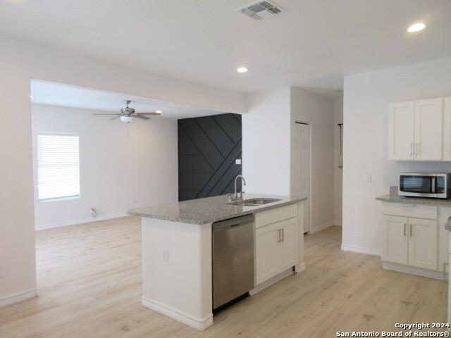 kitchen with stainless steel appliances, sink, white cabinets, and light wood-type flooring