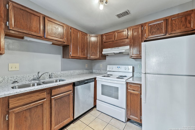 kitchen with light tile patterned flooring, light stone countertops, sink, and white appliances