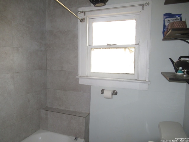 bathroom featuring tiled shower / bath, plenty of natural light, and toilet